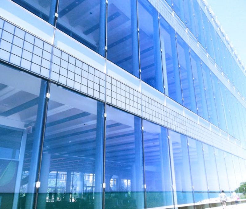 Contemporary glass building facade with reflections in the city, highlighting urban architecture.